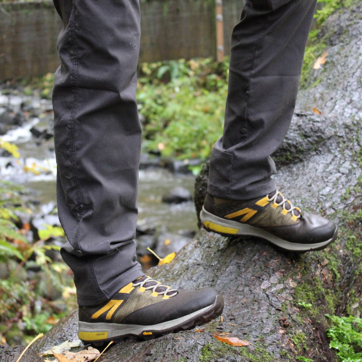 A good pair of beginner hiking boots like these Merrells standing on a wet log - HelloTrail