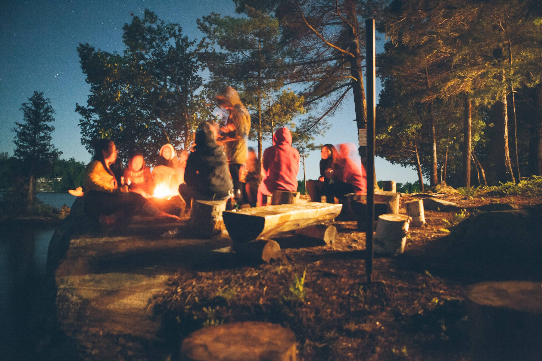 Friends sitting around a campfire at night - HelloTrail.com