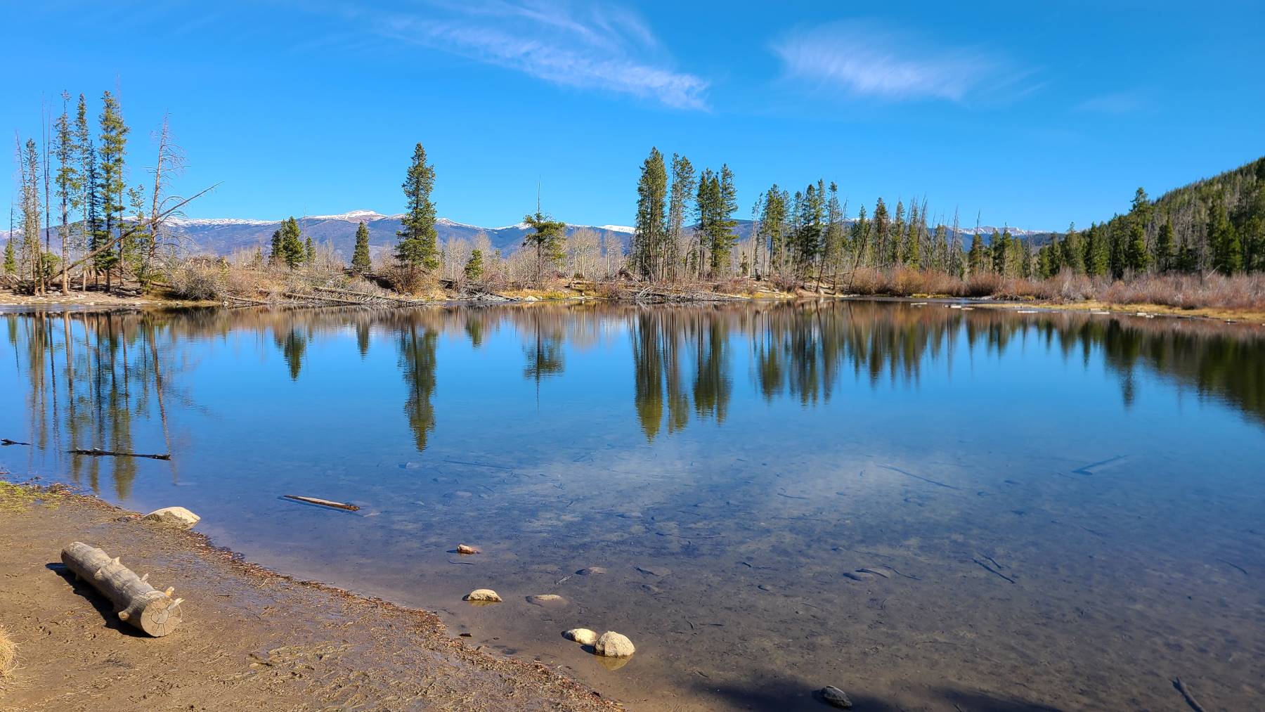 Hiking to Rainbow Lake in Frisco, Colorado with snowcapped mountains in the background.